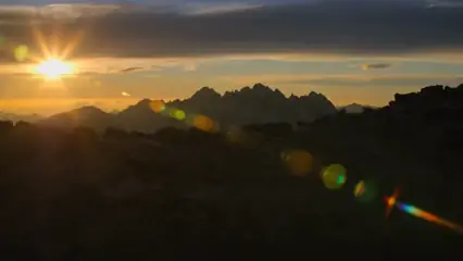 Sunset over a mountain ridge with lens flare